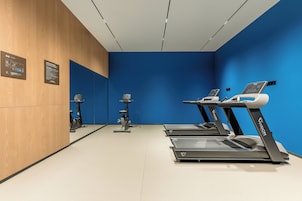 Un gimnasio con cintas de correr, una bicicleta estática y una bicicleta de spinning.