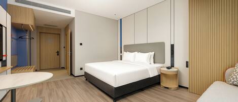 Una habitación de hotel moderna con una cama grande, una mesita de noche y un escritorio pequeño con una silla.