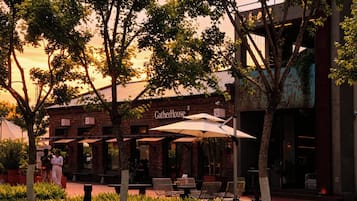 An outdoor seating area with tables and chairs, a brick building with a sign reading 'GatherHouse,' and trees in the background.