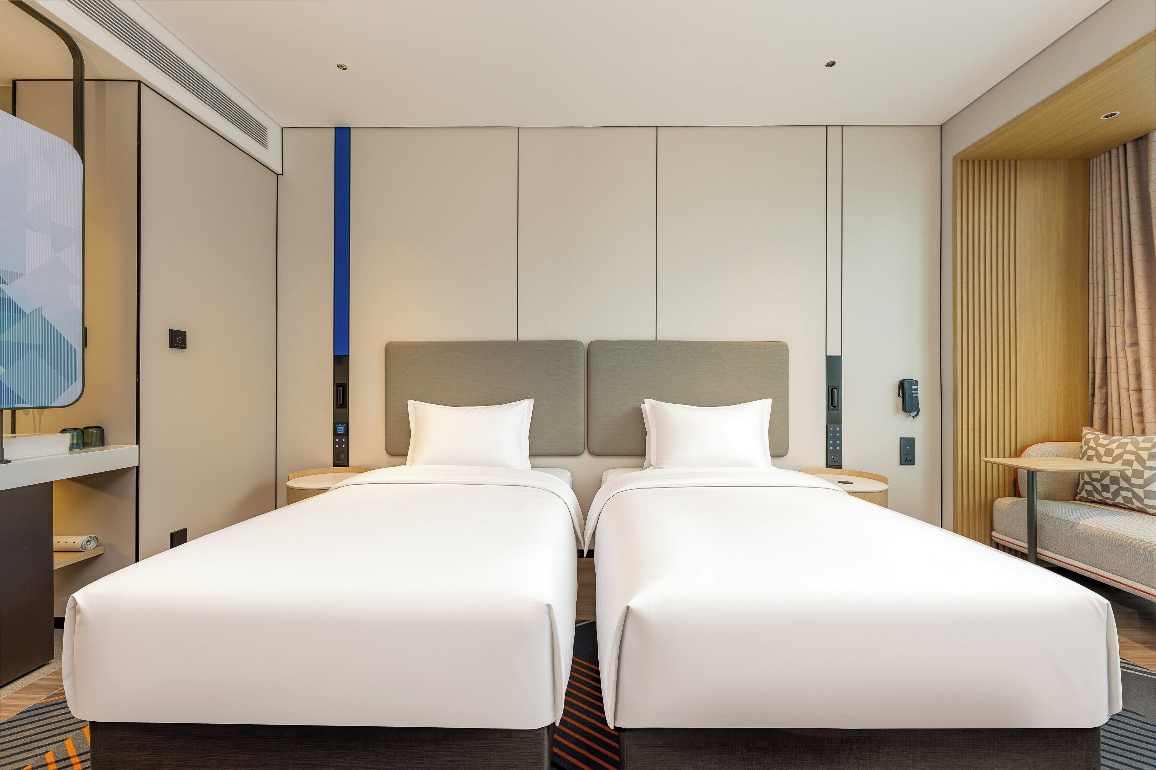 Ein Hotelzimmer mit zwei Einzelbetten, einem Schreibtisch mit Stuhl, einem kleinen Tisch und einem Sofa.