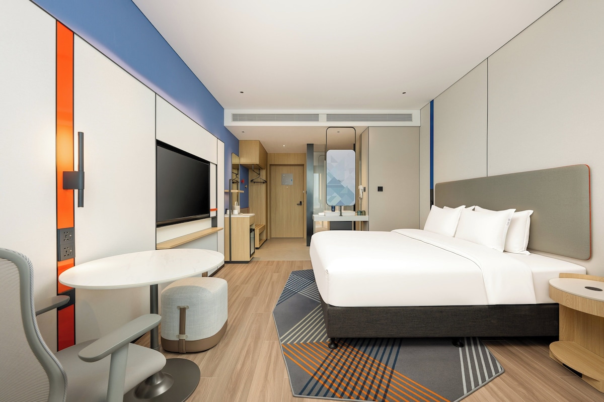 Una habitación de hotel moderna con una cama, televisión, escritorio y zona de estar.