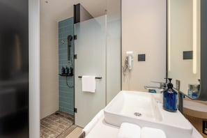 Un baño moderno con cabina de ducha de vidrio, un lavabo blanco y un espejo grande.