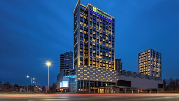 A Holiday Inn Express hotel with a modern design, featuring a prominent glass facade and a rooftop terrace. - Holiday Inn Express Qinhuangdao Haigang By IHG (Qinhuangdao)