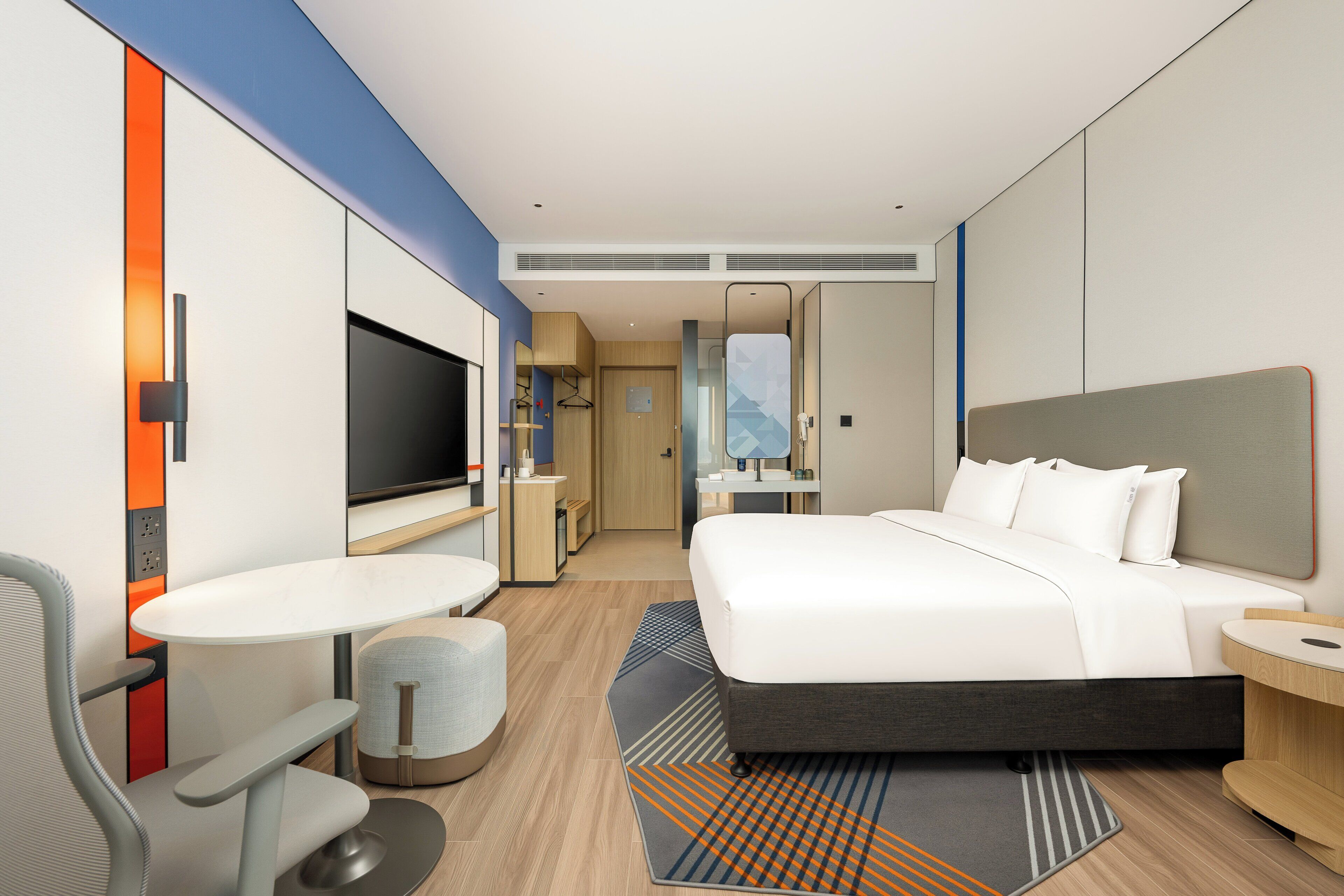 Une chambre d’hôtel moderne équipée d’un lit, d’une télévision, d’un bureau et d’un coin salon.