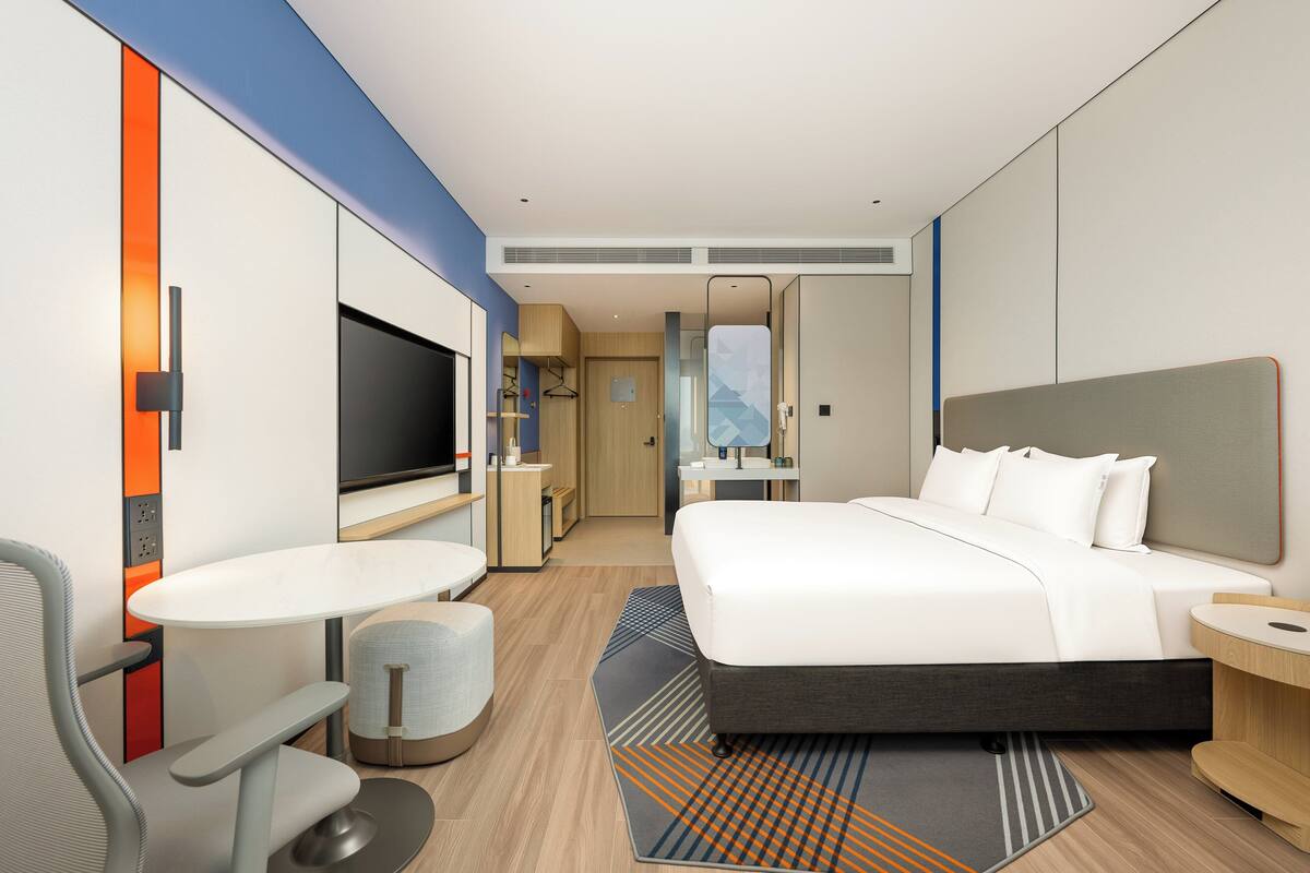 Una habitación de hotel moderna con una cama, televisión, escritorio y zona de estar.