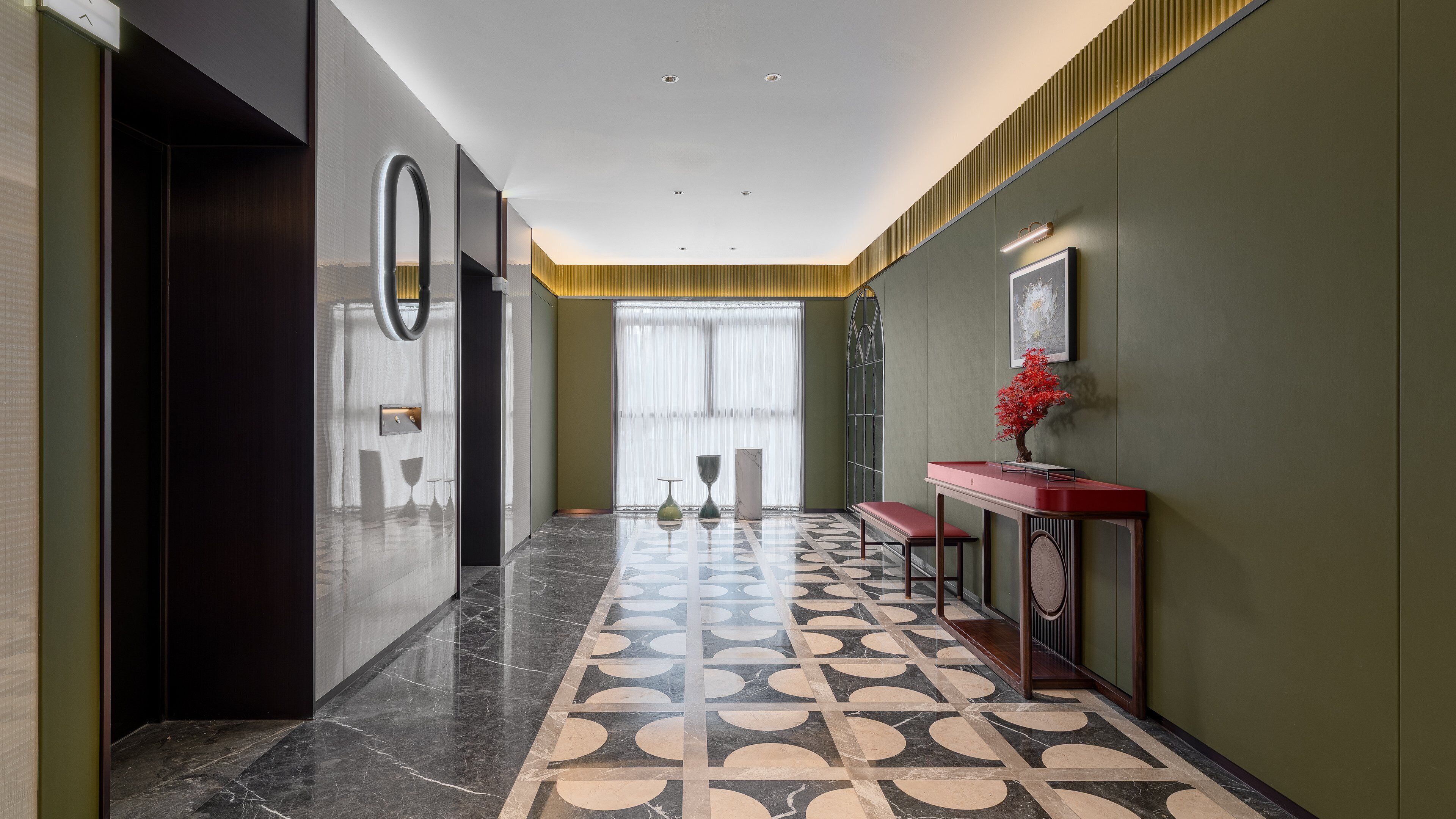 Um corredor com piso de mármore, um console vermelho e uma grande janela com cortinas leves.