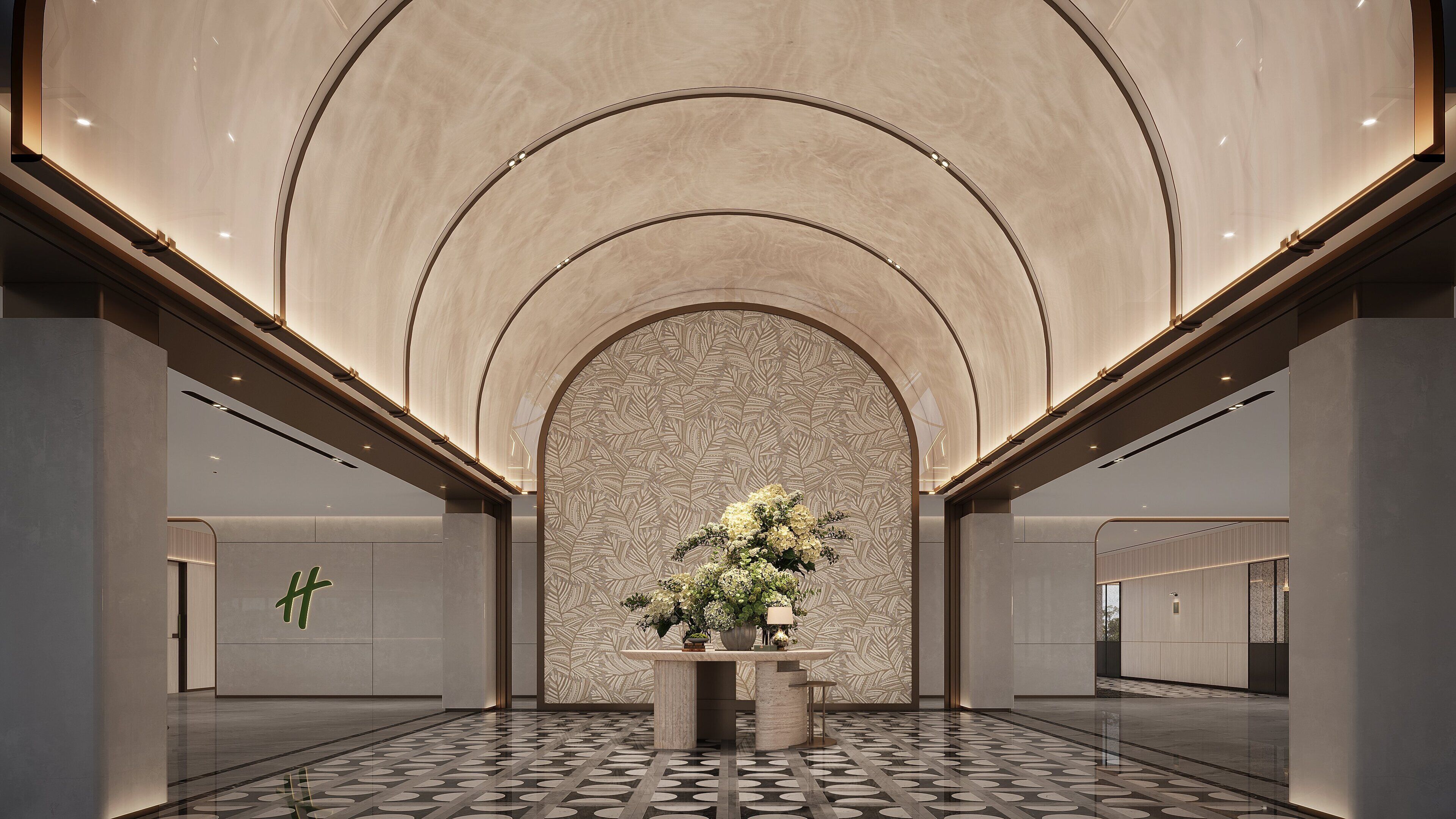 A spacious lobby with a high ceiling, a patterned wall, and a central floral arrangement.