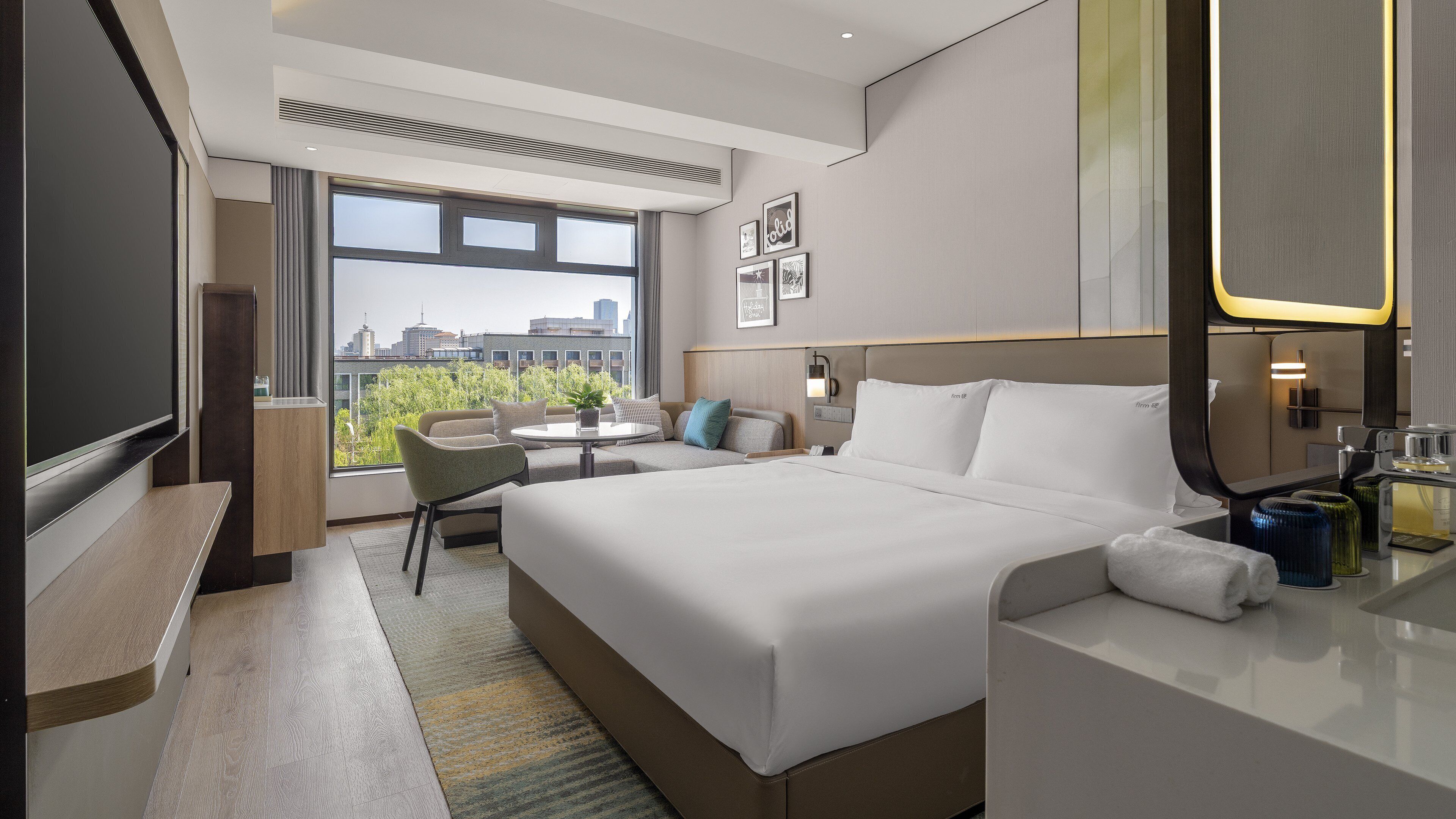 A modern hotel room with a large bed, a desk, a chair, and a television.