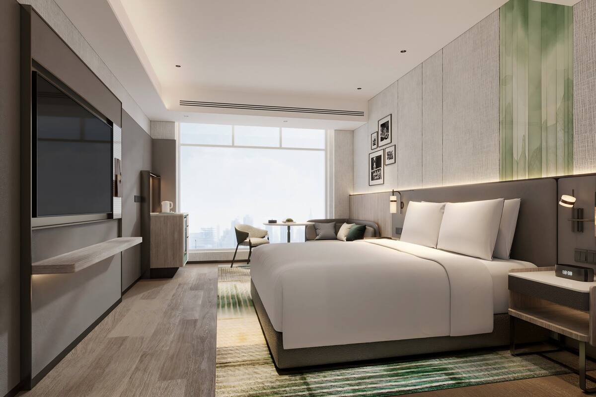 Een moderne hotelkamer met een groot bed, een bureau, een stoel en uitzicht over de stad.