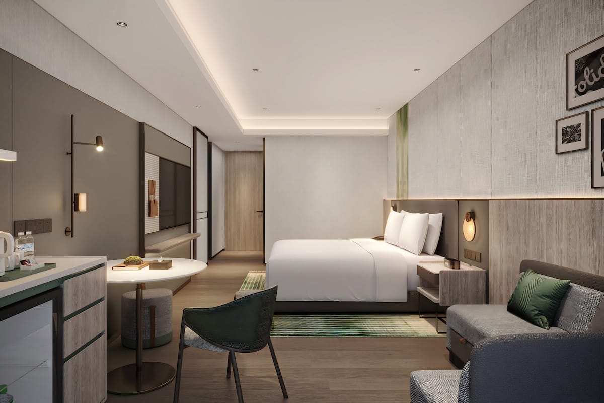 Een moderne hotelkamer met een bed, een bank, een bureau met stoel, een televisie en een badkamer.