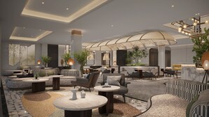 Una hall d'albergo moderna con aree salotto, una reception e una grande struttura a soffitto curva.