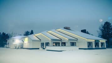 Un edificio amplio y moderno con tejado plano y numerosas ventanas, rodeado de nieve.
