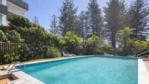 Ein Schwimmbecken mit Liegestühlen und einer Holzterrasse.