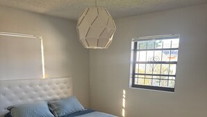 Ein Schlafzimmer mit einem Bett, einem Fenster und einer Deckenleuchte.