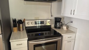 Eine Küche mit einem Edelstahlherd, einer Kaffeemaschine und einem Besteckhalter mit Messern.