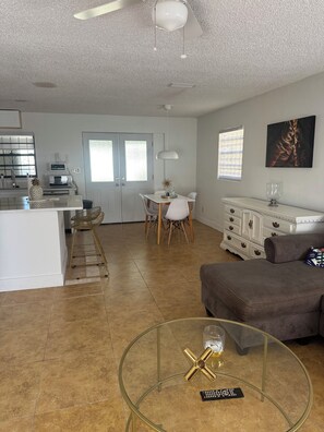 Ampla sala de estar com uma mesa de jantar, um sofá e uma mesa de centro de vidro.