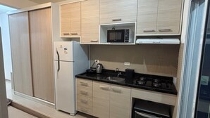 A modern kitchen with a built-in microwave, a kettle, and a stove.