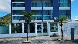 A modern multi-story hotel with a flat facade, large windows, and a parking area with palm trees.