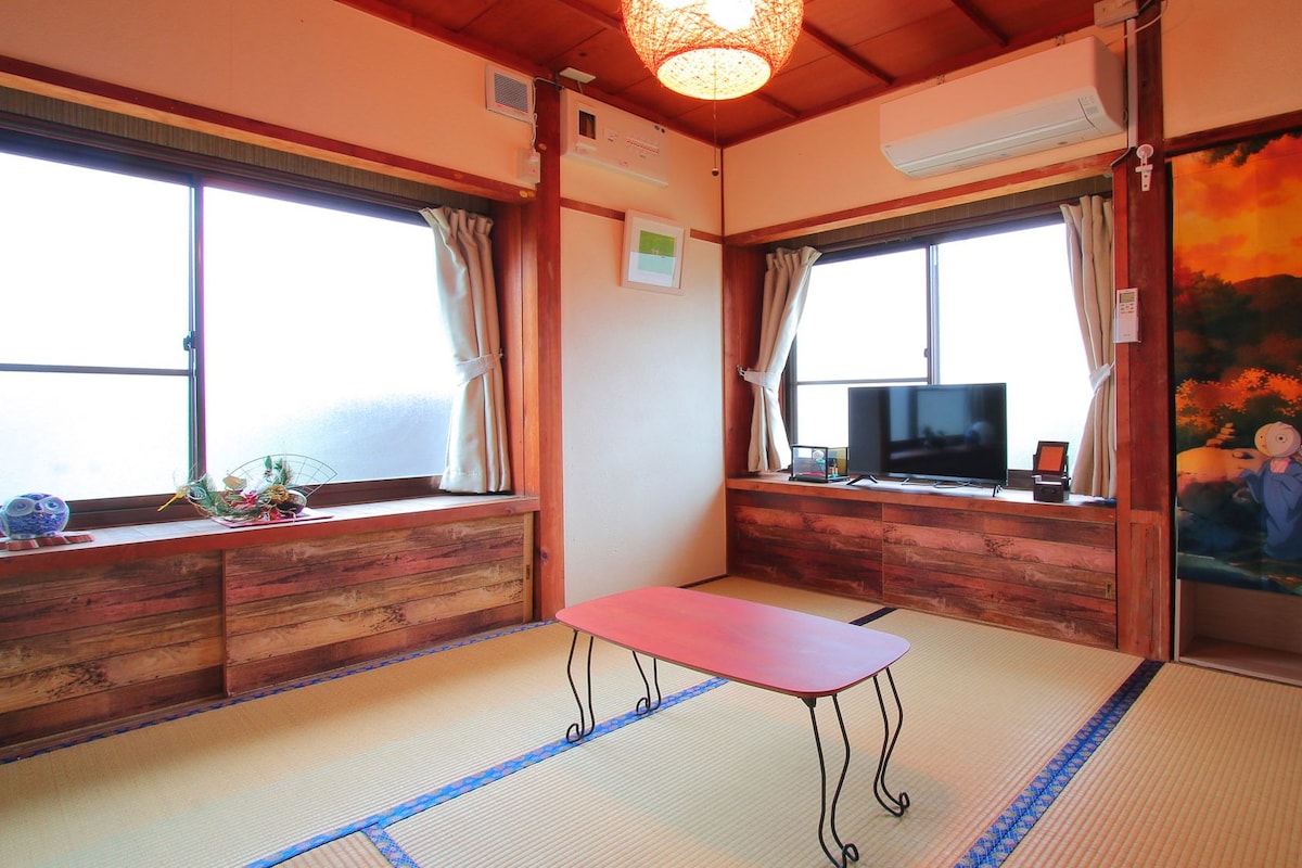 Una habitación japonesa tradicional con suelo de tatami, un televisor y un cuadro en la pared.