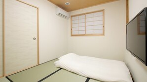 A room with tatami flooring, a futon bed, a shoji screen, and a mounted TV. - Hitoyoshi Onsen Oga no Yado (Hitoyoshi)