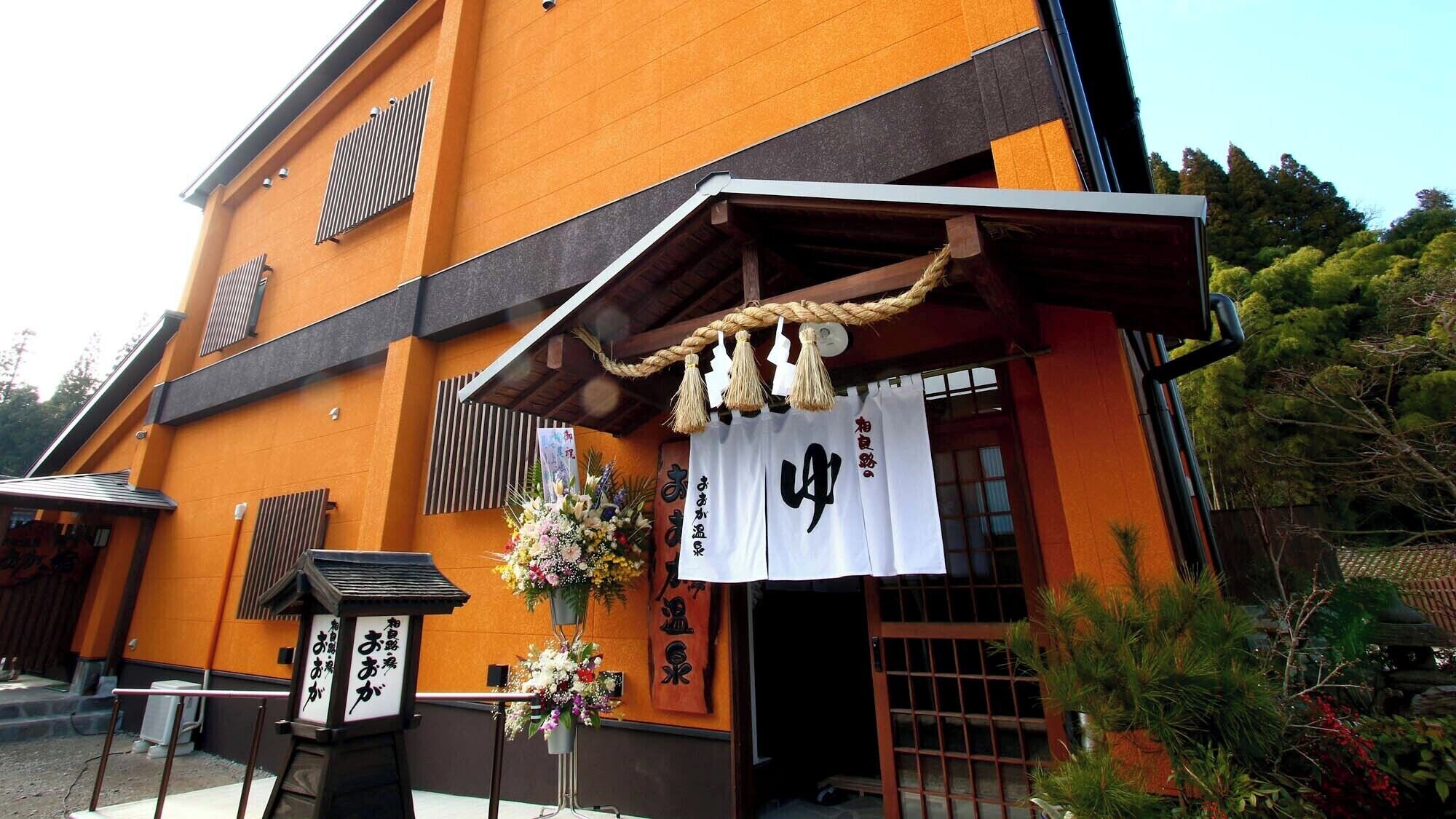A traditional Japanese building with a wooden entrance and a signboard with Japanese characters.