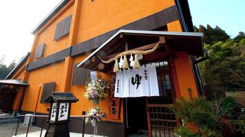 A traditional Japanese building with a wooden entrance and a signboard with Japanese characters.