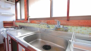 A kitchen with a stainless steel sink, a gas stove, and a window with a wooden frame. - Hitoyoshi Onsen Oga no Yado (Hitoyoshi)