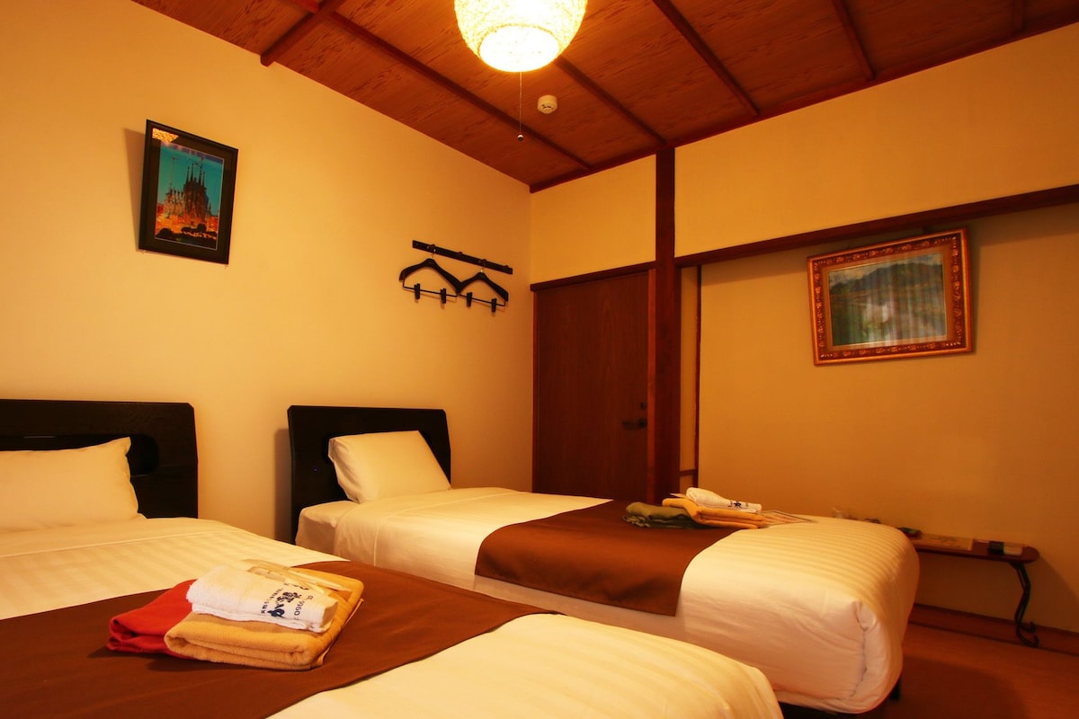 Habitación de hotel con dos camas, techo de madera y un cuadro en la pared.