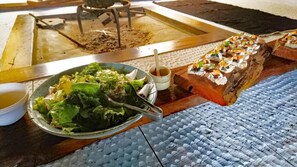 Una mesa de comedor con una ensalada, un tazón de sopa y una tabla de madera con sushi.