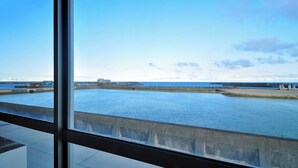 Een havenzicht met water, een kade en gebouwen op de achtergrond.