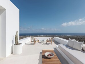 A rooftop terrace with a white sofa, two wicker chairs, a small table, and a potted cactus. - Villa Anemos, Luxury Villa with Panoramic Views (Oia)