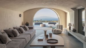 Ein modernes Wohnzimmer mit einer Couch, Sesseln, einem Couchtisch und Blick ins Freie.