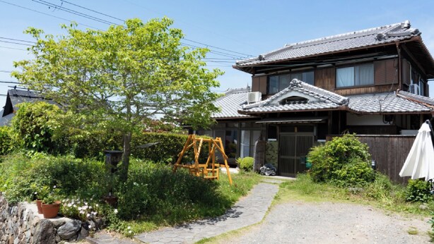 A traditional Japanese house with a tiled roof, a wooden gate, and a stone pathway leading to the entrance. - Farmhouse Nana (Kameoka)