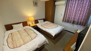 Une chambre d’hôtel avec deux lits, une table de chevet avec une lampe, un appareil de climatisation et un téléviseur.