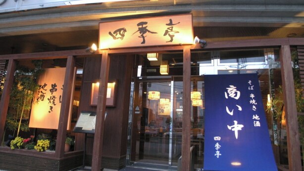 L’entrée d’un restaurant, avec une enseigne en japonais, une façade en bois et une porte en verre.