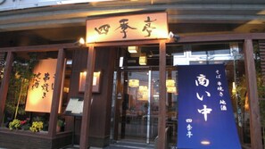 Een restaurantingang met Japanse borden, een houten gevel en een glazen deur.