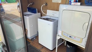 Un espace buanderie compact comprenant un lave-linge, un sèche-linge et un évier avec un tuyau.