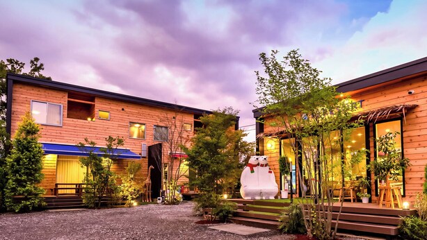 A modern building with a wooden facade, a large giraffe sculpture, and a snowman statue in the courtyard. - Kawaguchiko Villa FJ Resort (Fujikawaguchiko)