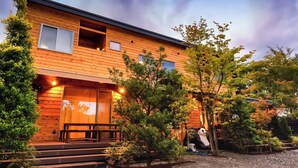 A wooden cabin with a porch, steps, and a panda statue. - Kawaguchiko Villa FJ Resort (Fujikawaguchiko)