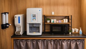 Une petite cuisine équipée d’une machine à café, d’un four à micro-ondes et d’une étagère contenant des articles de toilette.
