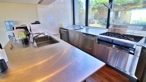 Una cocina moderna con electrodomésticos de acero inoxidable, un ventanal y vistas al exterior.