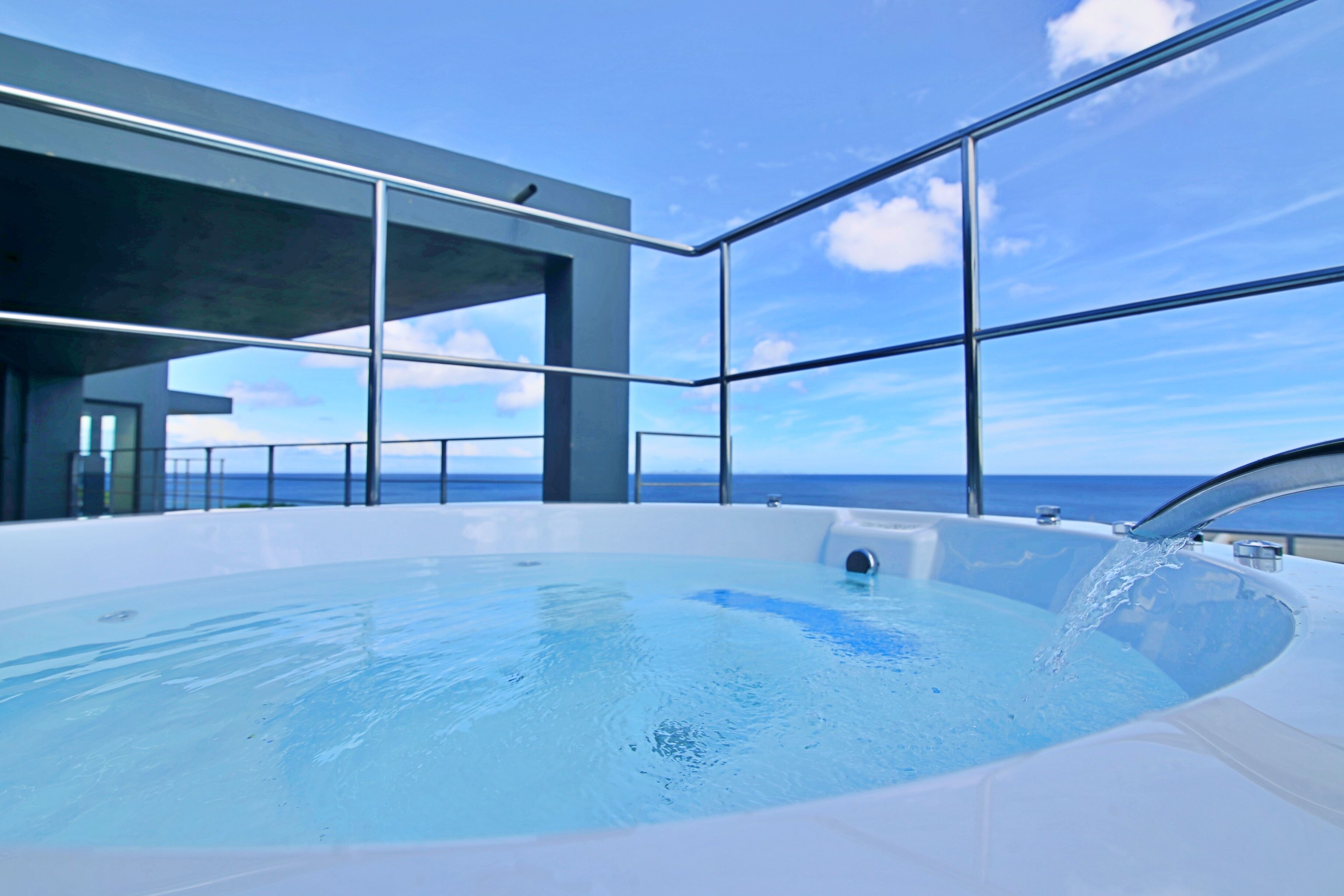 Une piscine intérieure moderne offrant une vue dégagée sur l’océan grâce à de grandes baies vitrées.