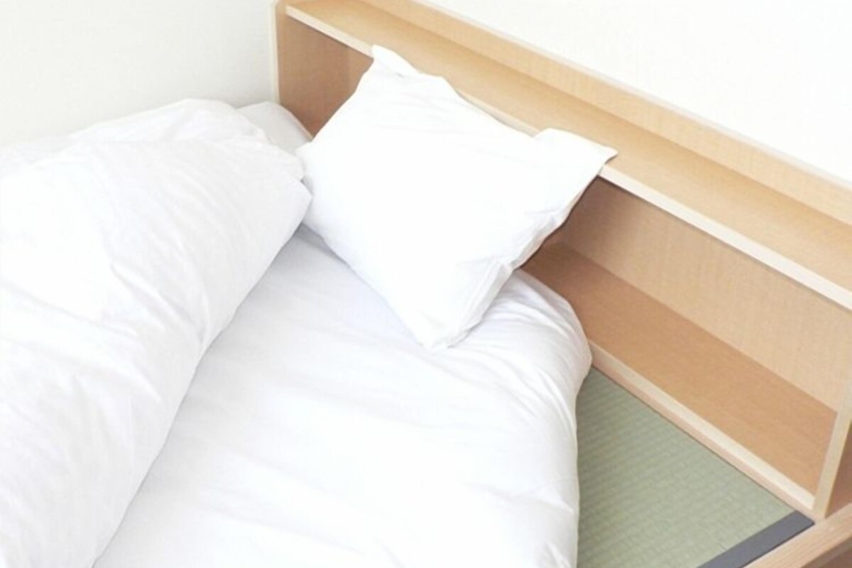 Una cama con ropa de cama blanca y cabecero de madera.