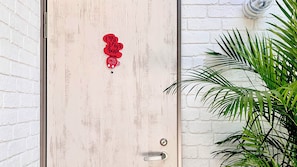 A wooden door with a red sticker that reads "Old Spice Boogie." - Sparky's House / House II (Naoshima)