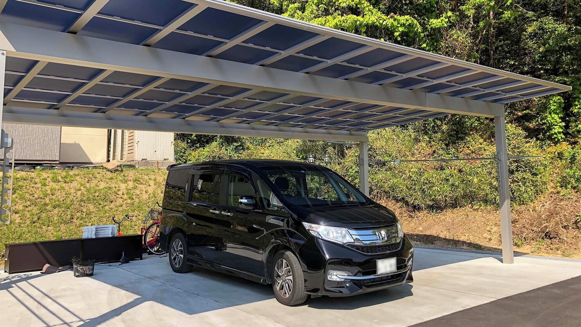 A black station wagon parked under a solar panel-covered carport.