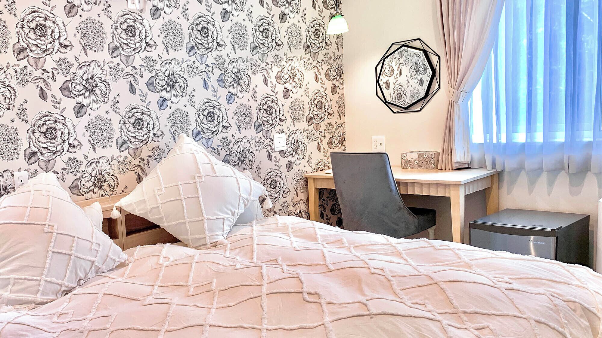 A bedroom with a bed, a desk, and a chair.