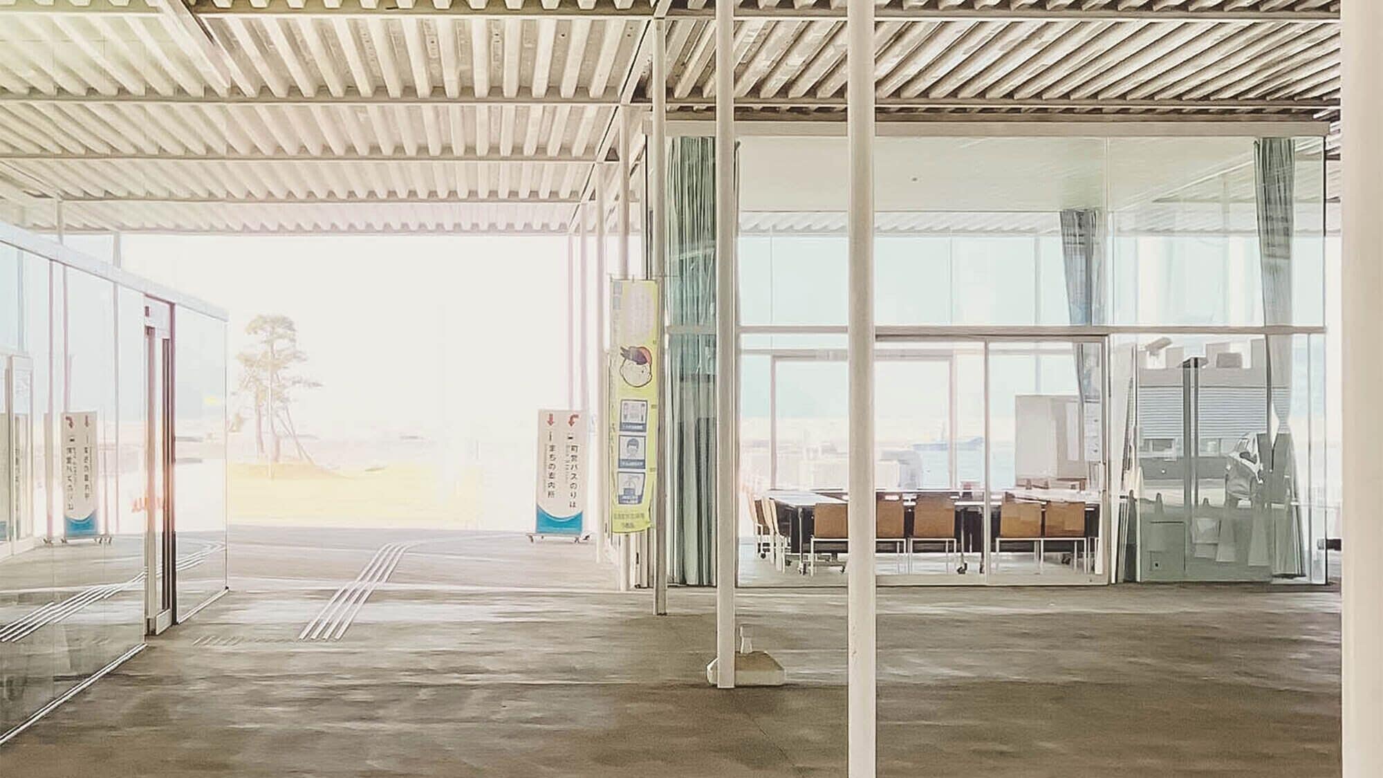 A spacious indoor area with a high ceiling, large windows, and a view of the cityscape.