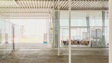 A spacious indoor area with a high ceiling, large windows, and a view of the cityscape.