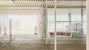 A spacious indoor area with a high ceiling, large windows, and a view of the cityscape. - Sparky's House / House II (Naoshima)