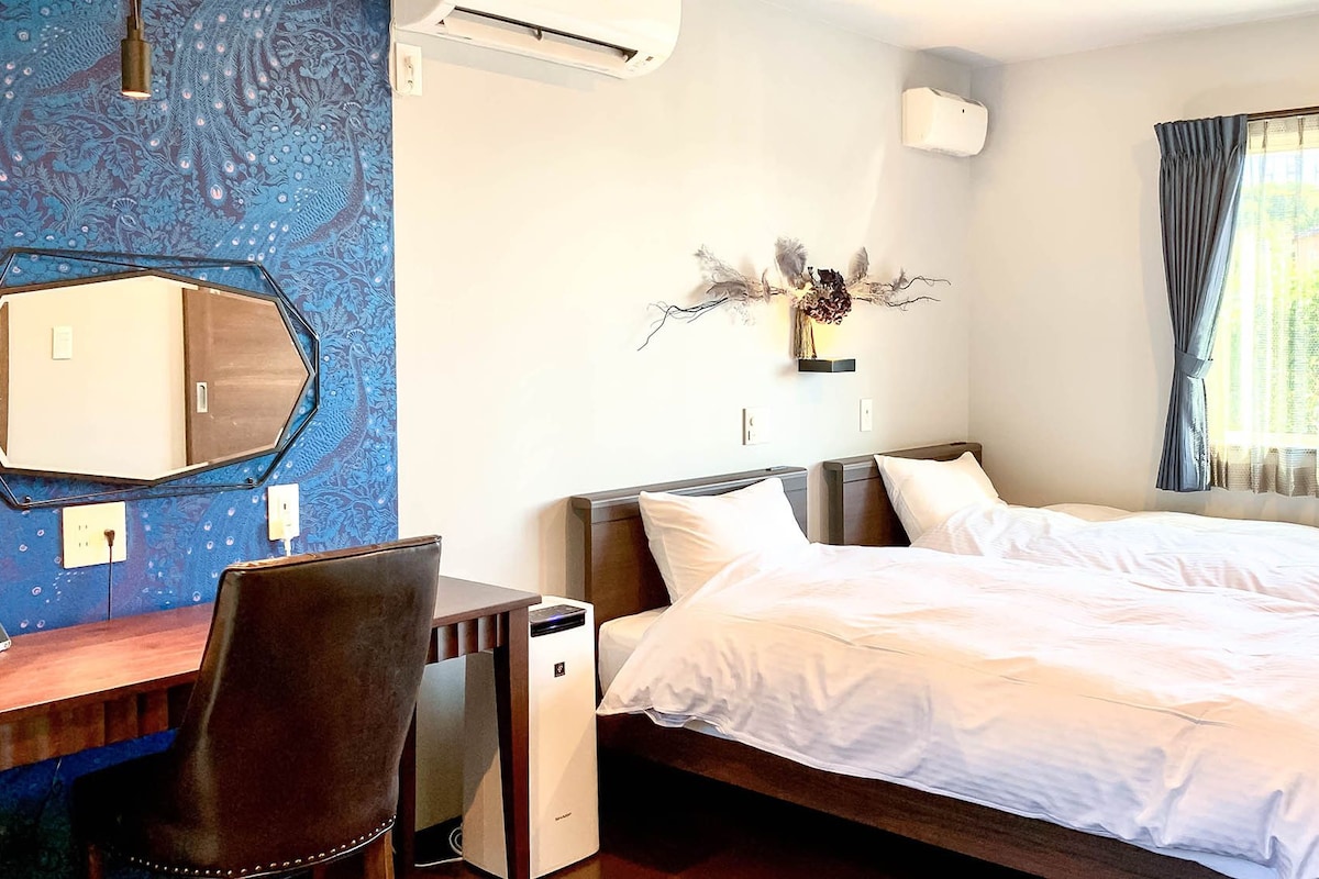 A hotel room with a bed, a desk, a chair, and a decorative wall piece.